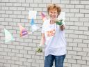 Vrijwilliger staat lachend met onkruid in haar handen tijdens NLdoet